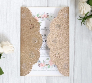 Macro detail of laser-cut rose patterns on a gold glitter wedding invitation card