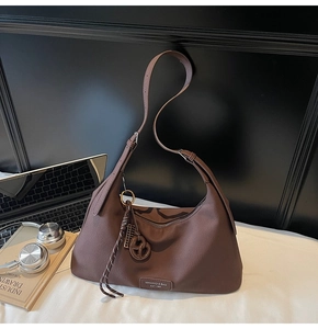Detail of dark brown leather hobo bag featuring litchi texture and branded nameplate