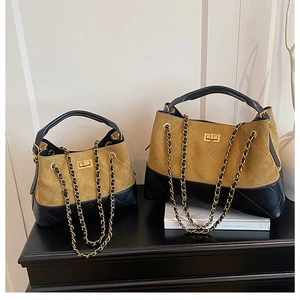 Detail of color-block bucket bag showing suede contrast and gold chain strap in two sizes