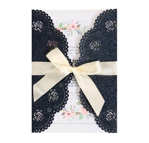 Intricate laser-cut navy glitter wedding invitation with cream satin ribbon and floral insert
