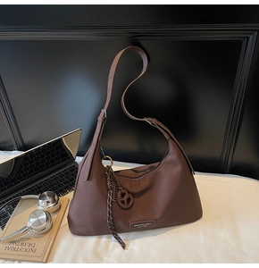 Close-up of brown litchi pattern crescent bag with adjustable strap and metal logo