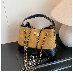 Detail of tan suede and black quilted leather handbag with gold chain strap and turn-lock