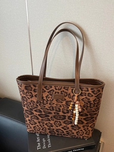 Vintage leopard print tote bag with suede texture and brown leather trim on black books