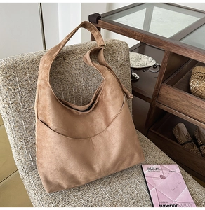 Détail du sac hobo en daim camel foncé avec coutures incurvées et large bandoulière