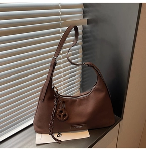 Detail of coffee brown pebble leather crescent bag with adjustable strap and shadow detail