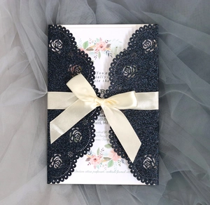 Detail of navy glitter laser cut wedding card with cream satin ribbon and floral insert