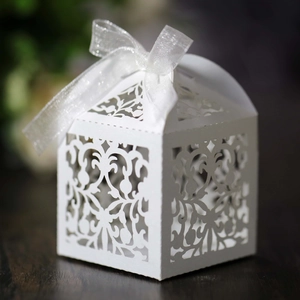 Detailed laser-cut white lace favor box with damascus patterns and a sheer ribbon bow