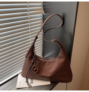 Close-up of brown crescent bag showing litchi texture leather and silver hardware