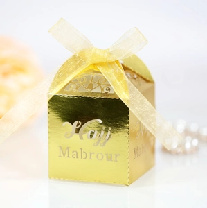 Macro detail of golden laser-cut gift box with Hajj Mabrour text and organza ribbon