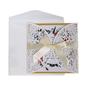 Laser-cut floral wedding invitation with cream ribbon bow and matching envelope set