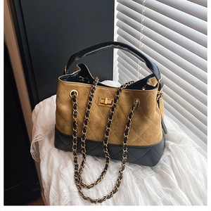 Close-up of contrast stitching, quilted texture, and golden twist lock on bucket bag