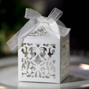 Close-up of laser-cut white candy box with elegant floral patterns and silver ribbon