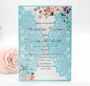 Macro detail of laser-cut floral pattern on light blue wedding invitation cards