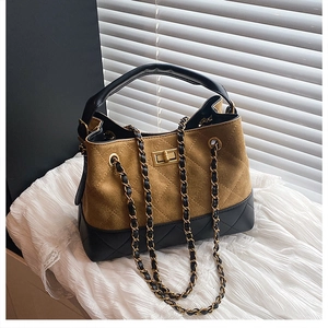 Detail of quilted bucket bag featuring dual-tone suede and chain strap on lace
