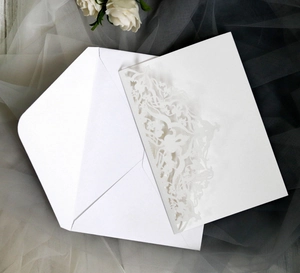 Detailed laser-cut hollow floral pattern on white wedding invitation suite