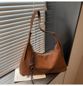 Detailed close-up of brown pebbled leather crossbody bag with light and shadow effects