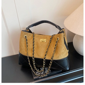 Detail view of mustard suede and black leather bucket bag with gold lock and chain