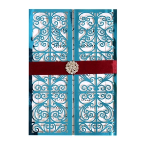 Détail d'invitation de mariage bleue découpée au laser avec ruban rouge et boucle strass