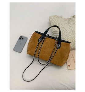 Detail view of large brown suede tote bag with chain strap and silver eyelet accents