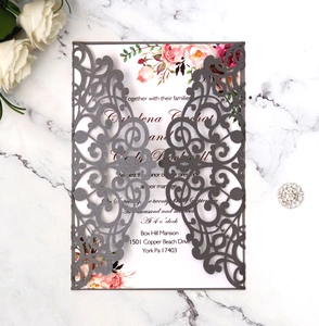 Close-up of laser-cut burgundy invitation with floral insert on marble background