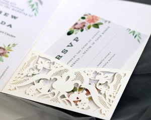 Macro detail of laser-cut floral lace patterns on ivory white wedding invitation card