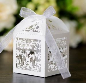 Macro shot of white laser-cut lace candy box with elegant ribbon bow for weddings