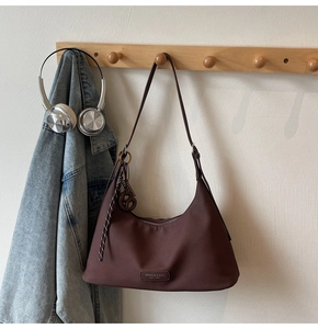 Close-up of brown hobo bag with matte leather texture and woven cord pendant detail