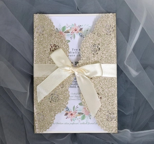 Detail of laser-cut rose invitation with gold glitter finish and cream satin bow ribbon