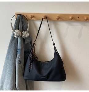 Detail of navy nylon hobo bag on wooden hanger with headphones and denim jacket