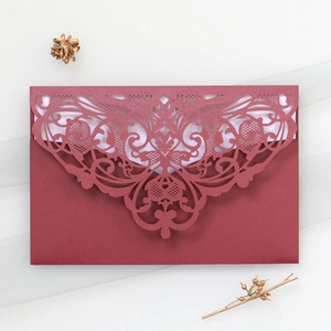 Macro detail of burgundy laser-cut lace invitation with elegant floral hollow patterns