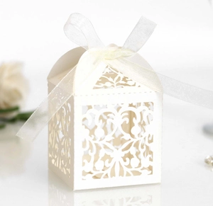 Detailed laser-cut vine patterns on a white lace wedding candy box with a satin ribbon bow