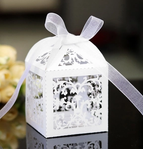 Close-up of white laser-cut lace wedding favor box with elegant organza ribbon bow