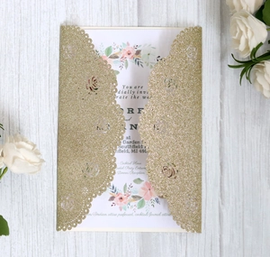 Detail view of laser-cut rose hollow invitation with gold glitter and floral inner card