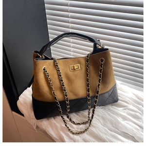 Detailed shot of brown suede and black leather tote bag with gold chain and turn-lock