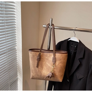 Close-up of brown faux leather tote bag with elephant charm and brand lettering