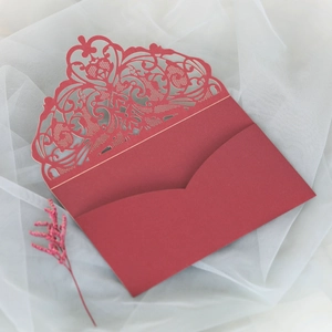 Detail of red laser-cut lace wedding invitation with intricate floral patterns on white mesh