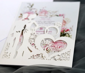 Detail of laser-cut wedding invitation featuring Mr & Mrs heart and floral ivory card