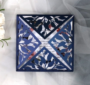 Detail of laser-cut leaf pattern on dark blue wedding invitation card with white inner sheet