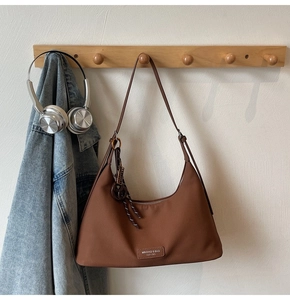 Detailed view of dark brown moon-shaped crossbody bag with brand plate and metal zipper