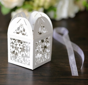 Detailed laser-cut vine design on white candy gift box with a light purple ribbon bow