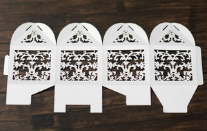 Detailed flat layout of white laser-cut lace candy box with intricate floral patterns