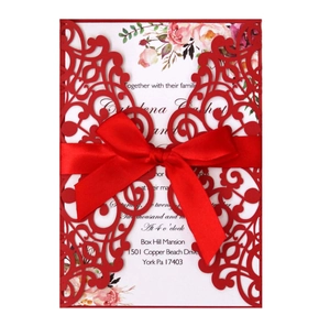 Detailed laser-cut pattern on burgundy wedding invitation with pink floral inner page