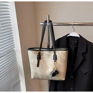 Detail of beige textured tote bag with black straps and fashion bags engraving