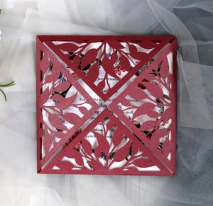 Macro detail of laser-cut burgundy wedding invitation with elegant leaf pattern