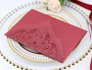 Detailed laser-cut lace design on burgundy wedding invitation card for elegant events