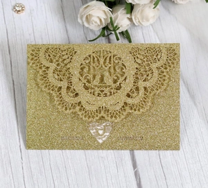 Detail of laser-cut lace pattern on gold glitter wedding invitation card with heart cutout