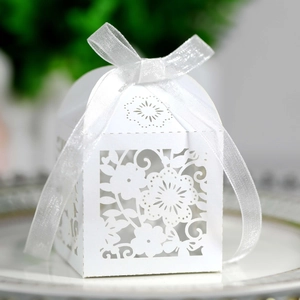 Macro shot of white laser-cut floral gift box with translucent ribbon on ceramic tray