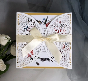 Elegant laser-cut rose wedding invitation with cream silk bow and floral insert