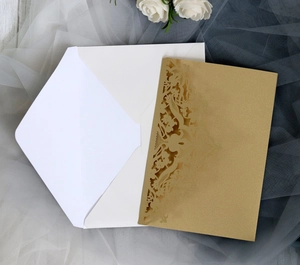 Detail of laser-cut gold hollow card with white envelope on elegant mesh background