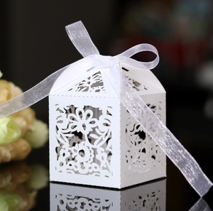 Elegant white laser-cut wedding favor box with floral patterns and a silk ribbon bow